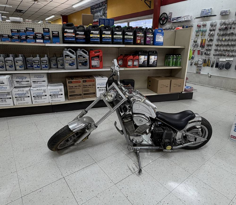 A custom motorcycle on display beside the shop's parts shelves